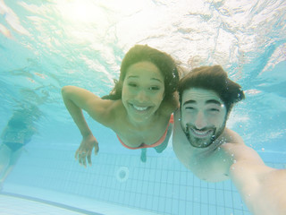 Handsome couple taking selfie under the water in swimming pool