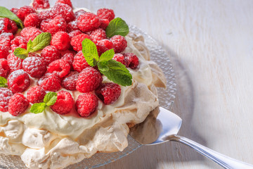 Meringue Pavlova  with whipped cream and fresh raspberries.