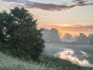 Beautiful vibrant Summer sunrise over English countryside landsc