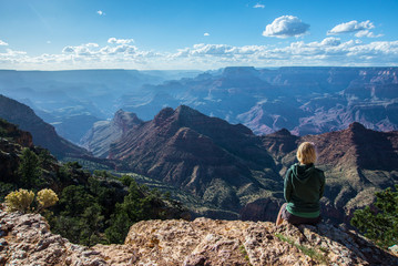 Fototapeta premium Girl sitting on rock overlooking the Grand Canyon National Park