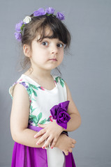 Small Caucasian with flower bond on head islated on grey background in studio