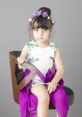 Small Caucasian with flower bond on head islated on grey background in studio