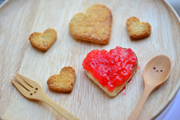Bread cutting and red strawberry jam in shape of heart and woode