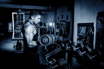 Young man exercising in dark and old gym