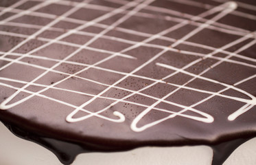 Close-up part of the chocolate Cake with the white lines and frozen drops - food background