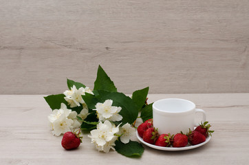Flowers of jasmine, white empty mug, strawberries, place for text