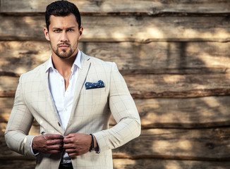 Portrait of young beautiful fashionable man against wooden wall.