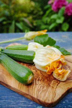 Flowering and ripe zucchini on olive wood plank and deep blue table top