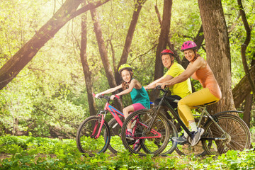 Active smiling family on bikes in the sunny forest