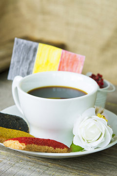 cookies with red black and yellow glaze as the Belgian flag colors. cup of coffee and a homemade flag of Belgium, decorative patriotic breakfast and lunch National Day. Selective focus photo image
