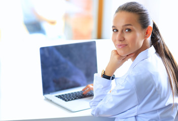 Beautiful young smiling female doctor sitting at the desk