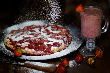 Smoothies and cake with strawberries sprinkled with icing sugar