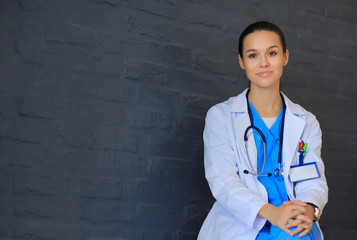 Young woman doctor sitting near wall