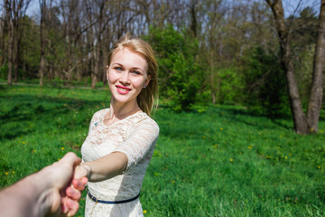 Obraz premium Lovely happy blonde holding my hand and dancing around in blossom garden. Point of view