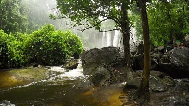 Water swirls around boulders after a long plunge from the natural waterfalls at Phnom Kulen National Park in Cambodia, with sound.