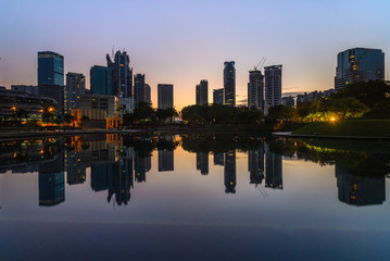 Fototapeta premium Tranquil blue hour pre dawn scene of Kuala Lumpur skyline reflected in calm lake water 