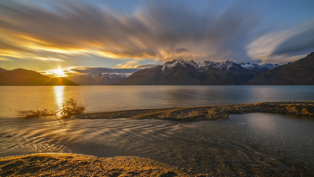 Long exposure image of sunrise at Lake Wakatipu, New Zealand with snow capped mountain in the background