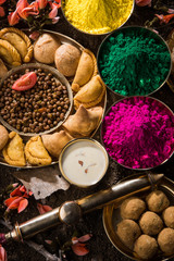 holi festival food with colours, indian festival holi, samosa, kachori, laddu, gujiya, palash flower, thandai, farsan, chana masala, puran poli or roti, indian festival of colours called holi