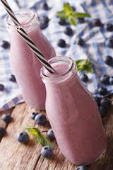Tasty blueberry milk beverage with mint in glass bottles close-up. vertical
