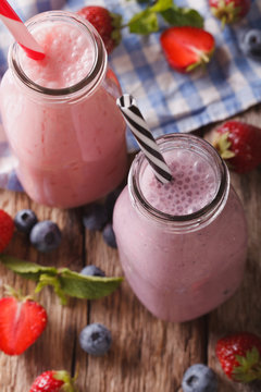 smoothie with strawberries and blueberries in bottles closeup. vertical top view
