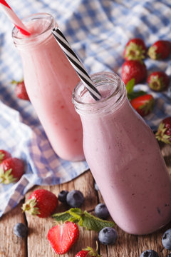Milkshakes with strawberries and blueberries in bottles close-up. vertical
