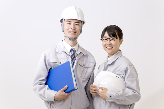 ファイルとヘルメットを持ちカメラ目線の男女作業員