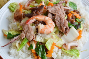 stir fried mixed vegetable with seafood and pork on rice