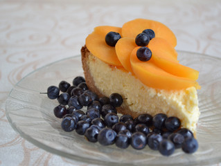 Aromatic cheesecake with apricot slices and blueberry on a glass plate. Healthy breakfast. Soft focus.