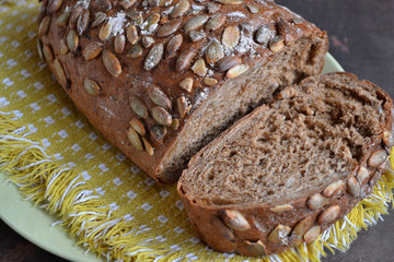 Rye bread with pumpkin seeds. Freshly baked savory pastry is on the yellow cloth napkin.