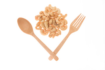 Wooden spoon and frok and roasted cashew nuts on white backgroun