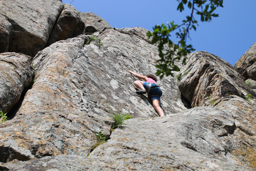 Girl rock climber climbs on a rock