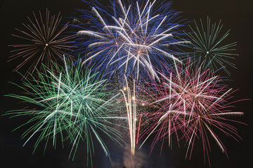 Fototapeta premium Green, blue, pink, red fireworks display - celebration and patriotism concept