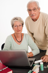 couple de s&eacute;niors devant un ordinateur avec des m&eacute;dicaments