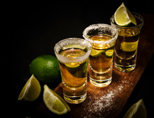 Mexican Gold Tequila with lime and salt on wooden table