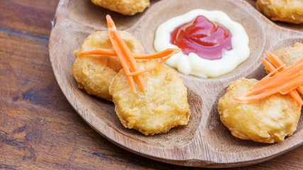 Chicken nuggets and sauce on a wooden background.