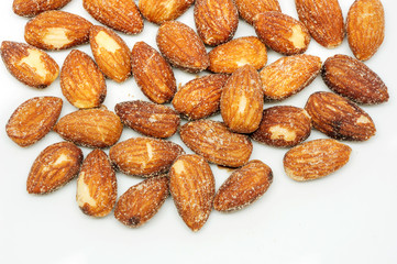 Almonds baking with salt on white background.