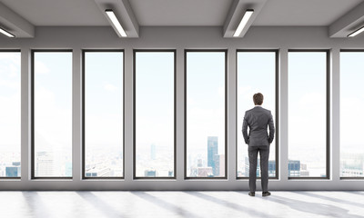Fototapeta premium Businessman in office room with big panoramic windows
