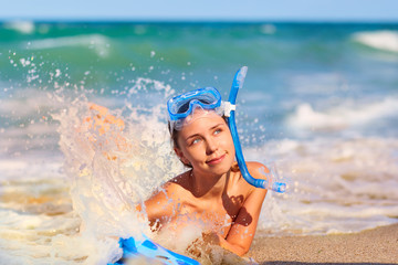 Concept summer totdyha sea, ocean, travel. Beautiful young girl on the beach wearing a scuba diving lying on the beach, beautiful splashes of water.