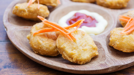 Chicken nuggets and sauce on a wooden background.