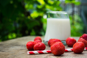 Glass of milk and ripe strawberry on the rustic wooden table