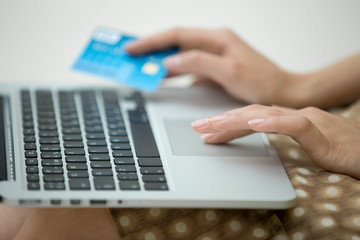 Close-up of beautiful woman hands using laptop and holding credit card, paying with credit card for online shopping on notebook. Side view. On-line payments concept image