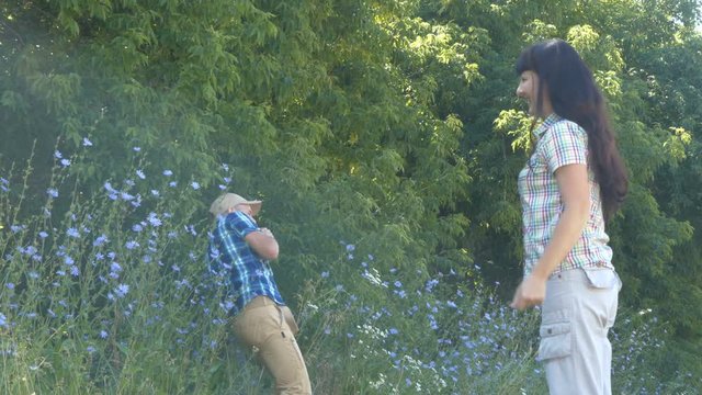 Large woman scolds the small man. Young couple having fight in summer park. A tall woman blames low husband.