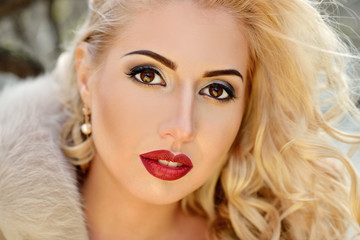 Fashionable portrait of lady with long hair in city. Image of blonde model on bright background. Young beautiful human in colorful coat in park. Adult female person wears street style outdoors