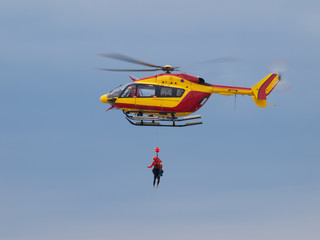 A red and yellow helicopter with rescuers