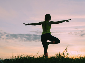 Fototapeta na wymiar Silhouette young woman practicing yoga at backyard