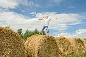 Naklejka na ściany i meble Teenager jumps on hay. Happy boy.