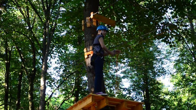 The girl the teenager overcomes obstacles between trees at height. Rope town.