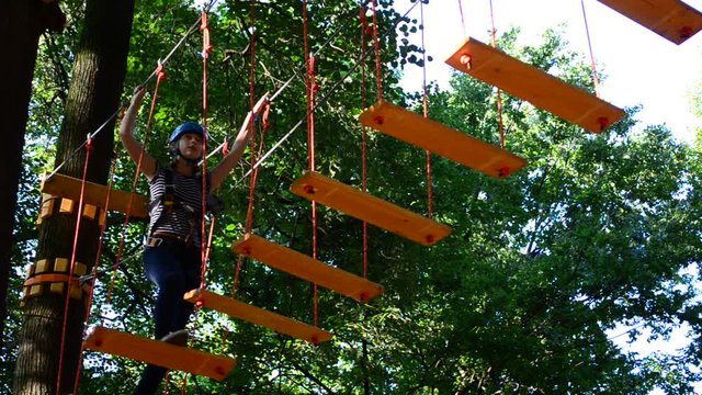 The girl the teenager overcomes obstacles between trees at height. Rope town.