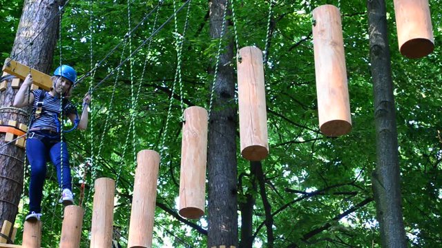 The girl the teenager overcomes obstacles between trees at height. Rope town.