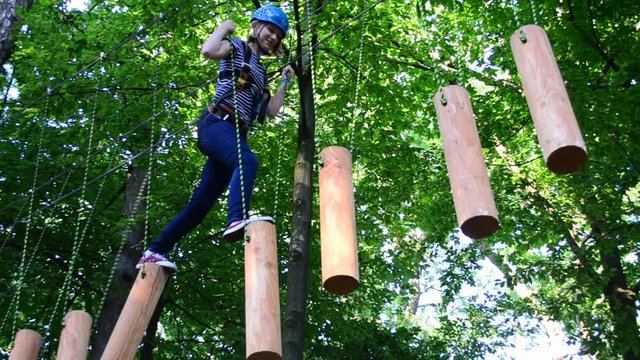 The girl the teenager overcomes obstacles between trees at height. Rope town.
